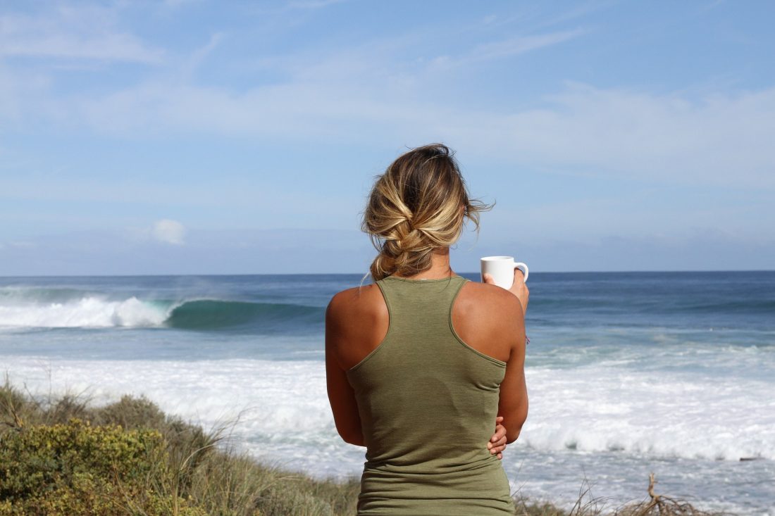 Woman drinking coffee by ocean